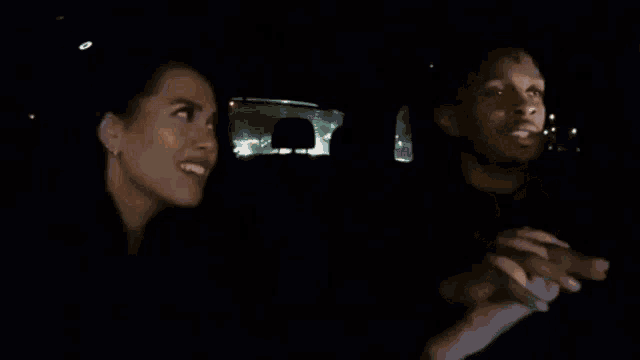 a man and a woman are laughing in a car at night