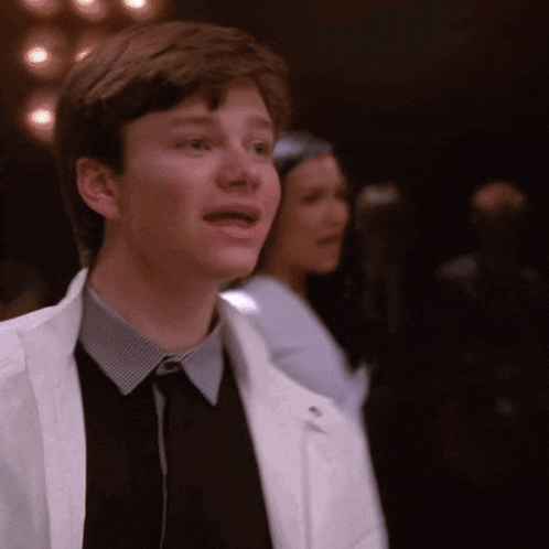 a young man in a white jacket and tie is standing in front of a woman