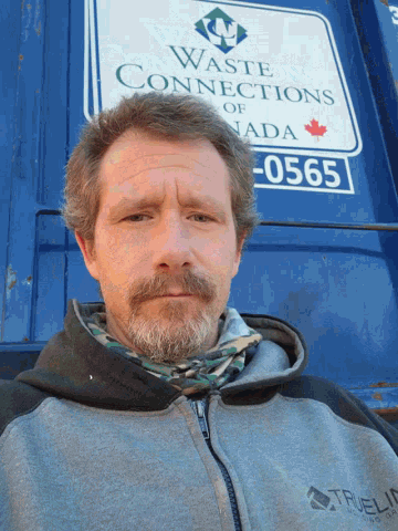 a man stands in front of a sign that says waste connections