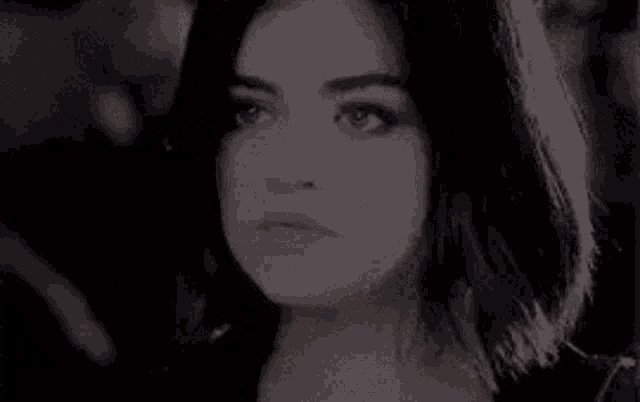 a close up of a woman 's face in a black and white photo with a blurred background .