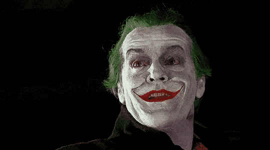 a close up of a man dressed as the joker with green hair and a red lip .