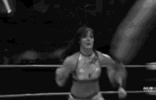 a black and white photo of a woman wrestling a man in a ring .
