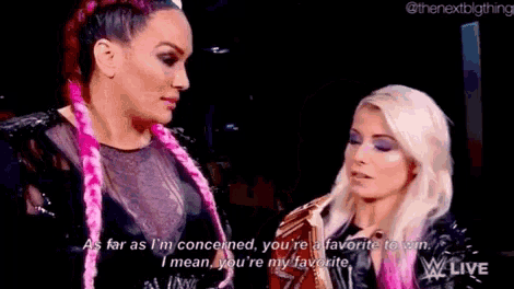 a couple of women are standing next to each other and talking to each other .
