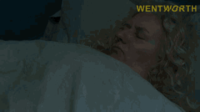 a woman laying in bed with the word wentworth on the bottom right
