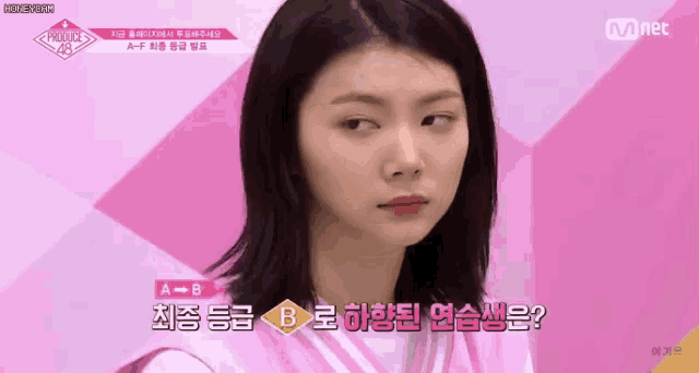 a girl is making a funny face in front of a pink background