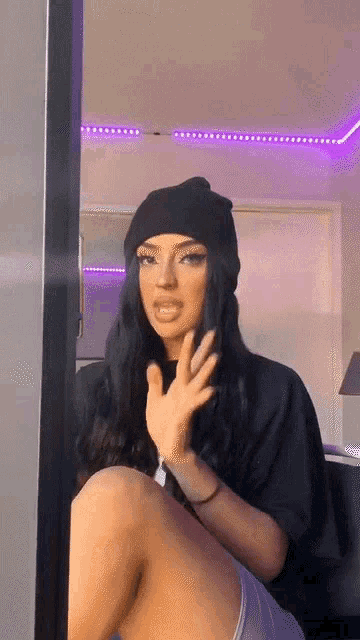 a woman wearing a black beanie and a black t-shirt is sitting on a couch .