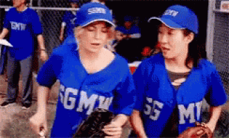 two female baseball players wearing blue uniforms with gmw on them
