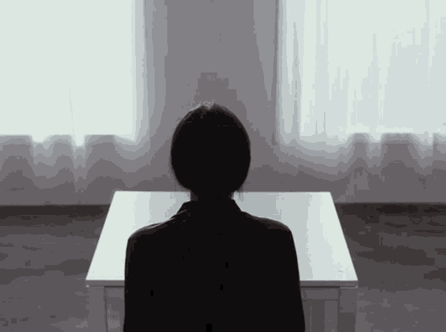 a woman is sitting at a table with her back to the camera