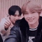 a couple of young men are sitting next to each other and smiling at the camera .