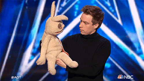 a man is holding a stuffed rabbit on a stage with nbc written on the bottom