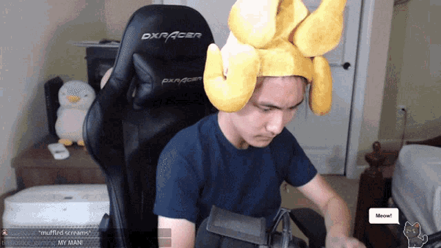 a man wearing a yellow hat is sitting in a dxracer gaming chair