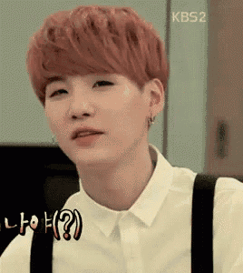 a young man with red hair is wearing a white shirt and suspenders and making a funny face .
