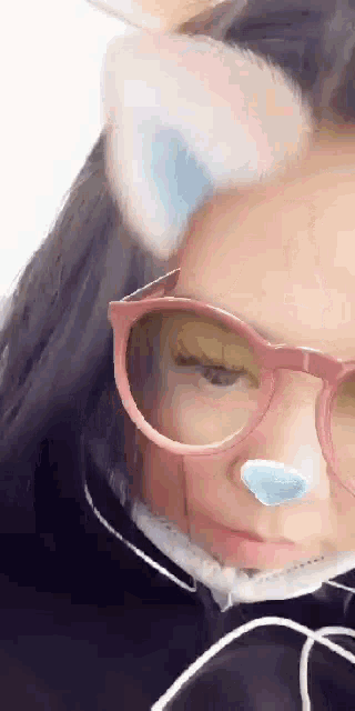 a girl wearing glasses and cat ears is making a cat face .