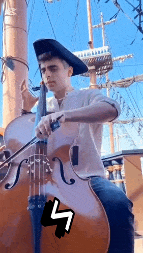 a man in a pirate hat is playing a cello on a boat