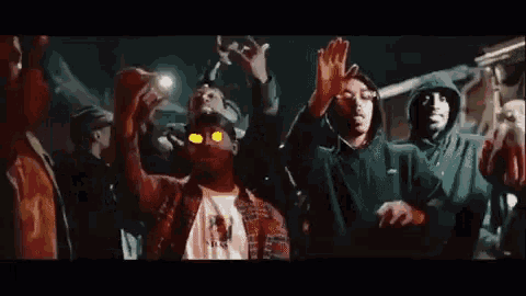 a group of people are standing in a crowd with their hands in the air and glowing eyes .