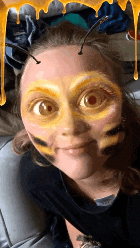 a girl with a bee face painted on her face looks at the camera