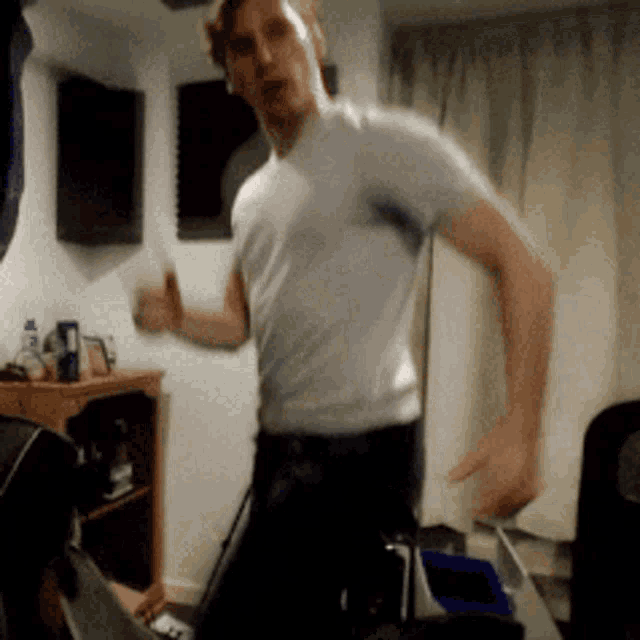 a man wearing a white shirt is dancing in a room