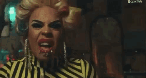 a drag queen is making a funny face while wearing a striped shirt and earrings .