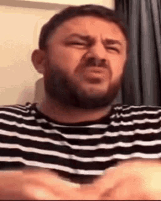 a man with a beard is wearing a black and white striped shirt .