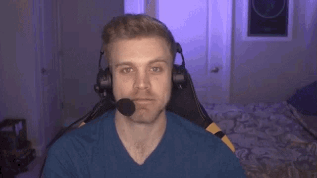 a man wearing headphones and a microphone is sitting in a chair and making a funny face .