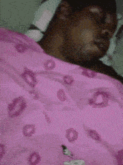 a person is laying on a bed with a pink blanket and a yellow bow on their head