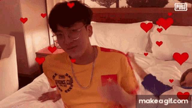 a man wearing a yellow shirt that says pubg on it sits on a bed
