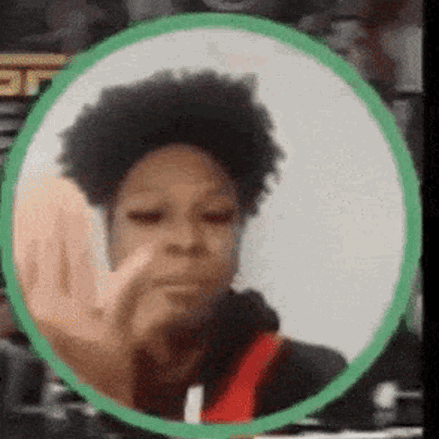 a woman is making a stop sign with her finger in a green circle .