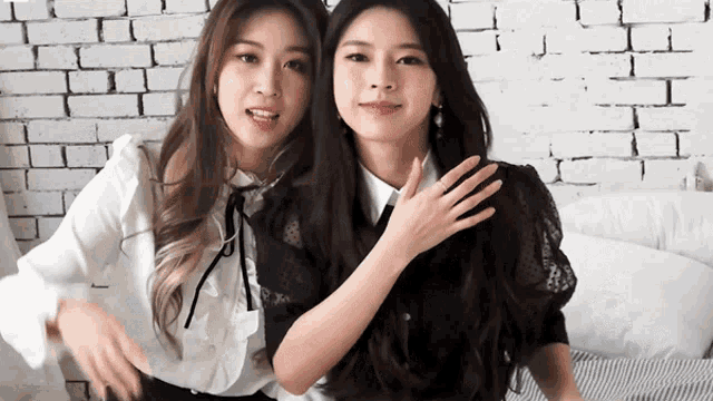two women standing next to each other with one wearing a white shirt