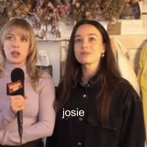 two women are standing next to each other and one is holding a microphone and the word josie is on the bottom of the picture .