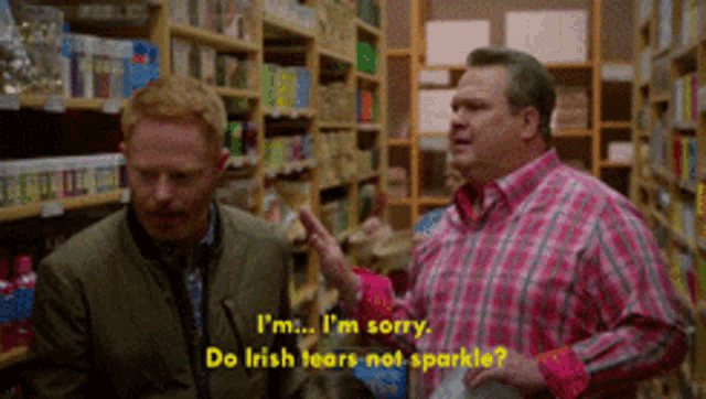 a man in a pink plaid shirt is talking to another man in a store