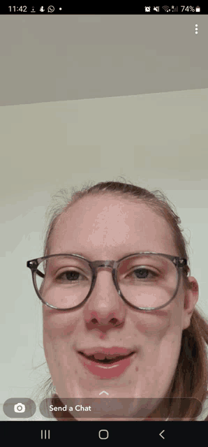 a phone screen shows a woman wearing glasses and a send a chat icon