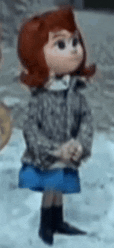 a doll with red hair and a blue skirt is standing in the snow wearing a jacket and boots .