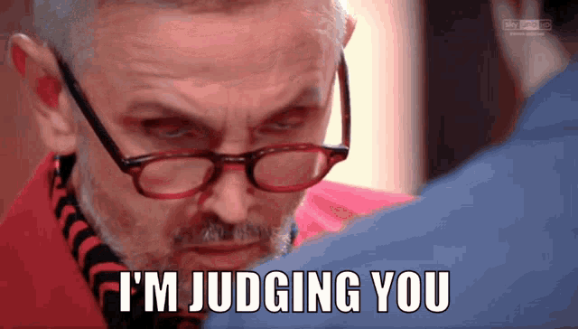 a man wearing glasses and a red jacket says " i 'm judging you "