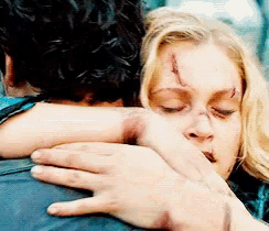 a woman with a scar on her face is hugging a man with his eyes closed