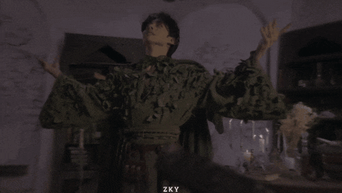 a man is standing in a dark room with his hand on his chest and the words zky on the bottom right