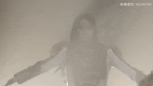 a woman with long hair is standing in front of a white wall