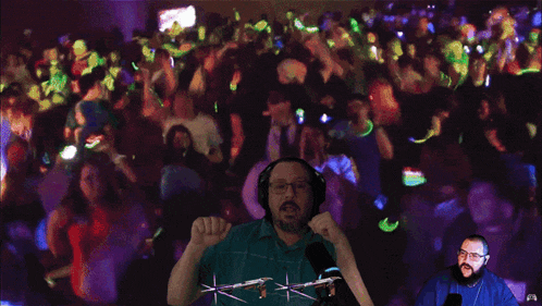 a man wearing headphones and glasses stands in front of a crowd