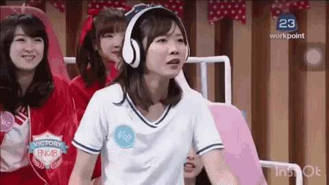 a woman wearing headphones and a white shirt is sitting in front of a group of girls .