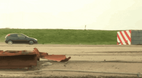 a car is driving down a road next to a red and white striped object