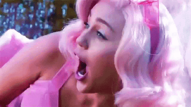 a woman in a pink wig is yawning with her mouth open .