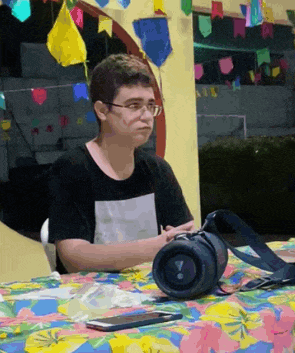 a young man is sitting at a table with a speaker and a cell phone