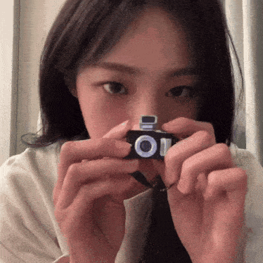 a woman is taking a picture with a small camera that says oi on it