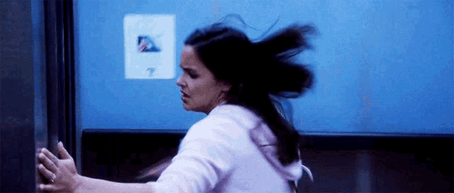 a woman with her hair blowing in the wind is standing in front of a blue door