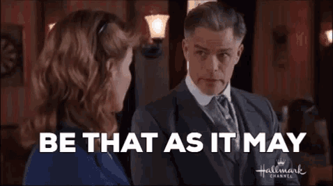 a man in a suit and tie is talking to a woman in a room .
