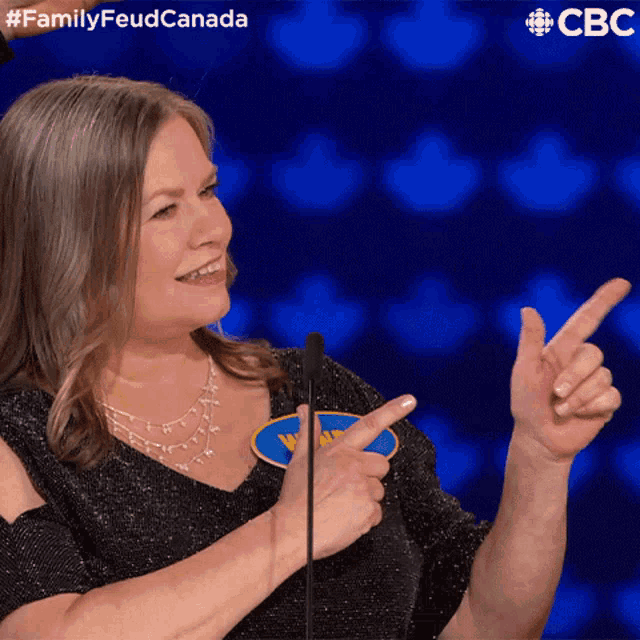 a woman pointing at something in front of a microphone with a cbs logo in the background