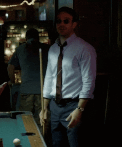 a man standing next to a pool table with a pool cue