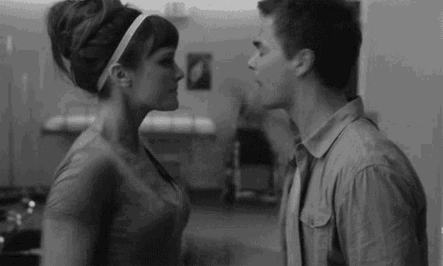 a black and white photo of a man and woman kissing .