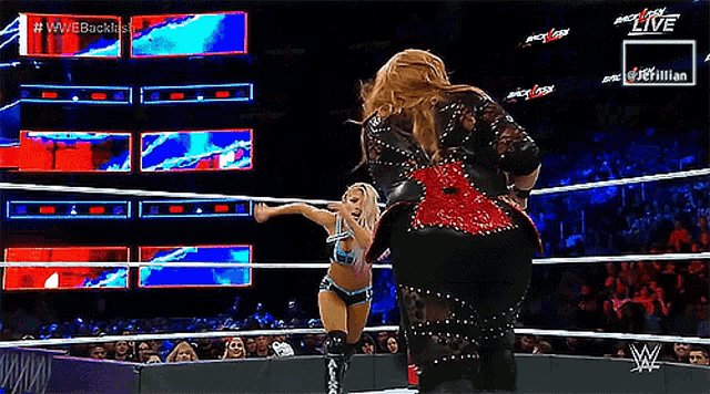 two women are wrestling in a wrestling ring with a referee in front of a crowd and a sign that says live