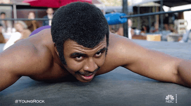 a man is laying on the ground in a wrestling ring with the hashtag youngrock