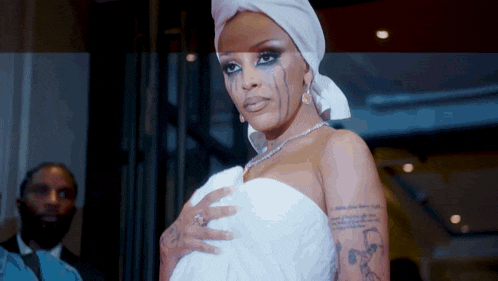 a woman with tears running down her face wears a white towel around her head